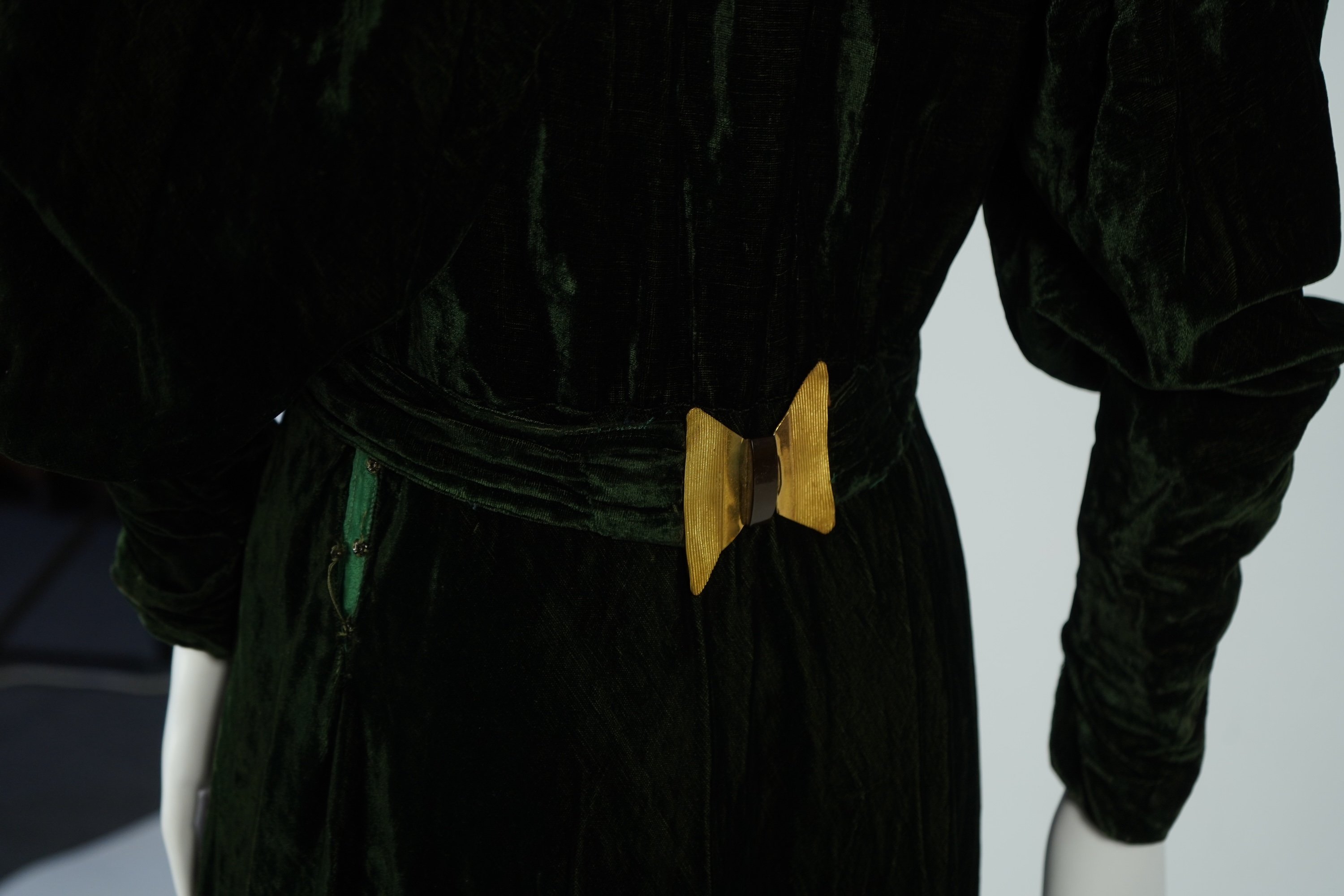 A flesh coloured 1930s lace evening dress and matching jacket together with a bottle green velvet evening dress and buckle belt and an unusual green shot silk pleated under skirt. Lace dress bust 32 inches. 156cm long. C